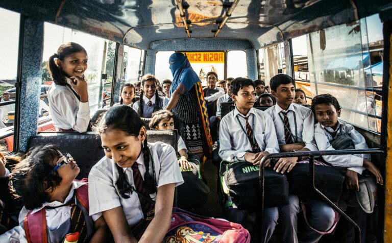 Group of school children in uniforms on a bus in Wadgaon, India.
